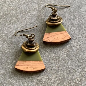 May include: A pair of green and brown wood earrings with a gold metal accent. The earrings are shaped like a fan and have a layered design.