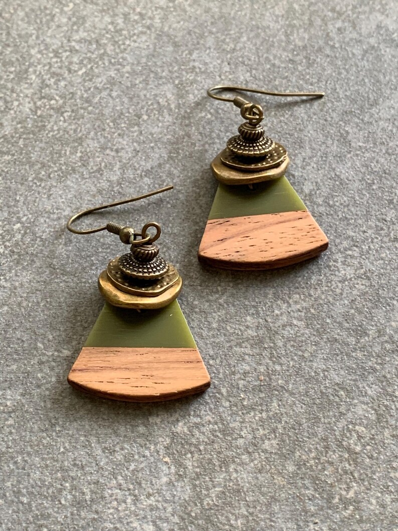 May include: A pair of green and brown wood earrings with a gold metal accent. The earrings are shaped like a fan and have a layered design.