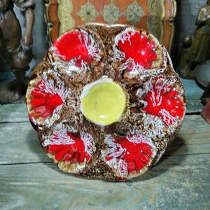 May include: A vintage ceramic oyster serving platter. The platter has a brown base with red and white floral designs and a yellow centre. A unique piece of home decor.
