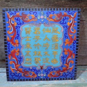 Peut inclure: Panneau décoratif carré bleu avec des motifs ornés de dragons et de fleurs rouges et oranges. Le centre présente un ovale bleu clair avec des caractères chinois dorés. Le panneau a une bordure bleu foncé.