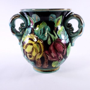Könnte beinhalten: Eine kleine, schwarze Keramikvase mit zwei Henkeln. Die Vase ist mit einem floralen Muster in Gelb-, Rot-, Grün- und Goldtönen verziert.