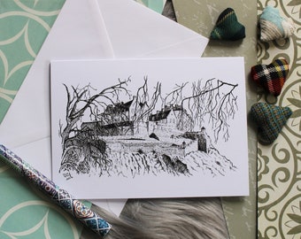 Puede incluir: Un dibujo en tinta negra y blanca de un edificio con un puente en frente. El dibujo está en una tarjeta blanca con un sobre blanco detrás. Hay pequeños corazones de tela de varios colores y patrones esparcidos alrededor de la tarjeta.