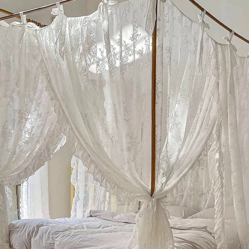 May include: White lace canopy bed curtains with ruffles, creating a romantic and elegant atmosphere in a bedroom.