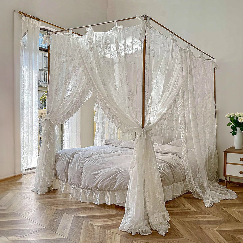 May include: White lace canopy bed with a white bedspread and ruffled trim. The canopy is tied back with white ribbons.