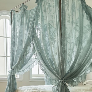May include: A light blue lace canopy bed curtain with ruffles. The curtain is draped over a bed frame and is tied back on each side.