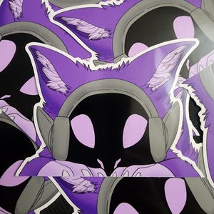 May include: A collection of stickers featuring a purple, stylized animal head with large ears and a headset. The animal has a black face with light purple eyes and feathery details in the ears. The headset is gray.