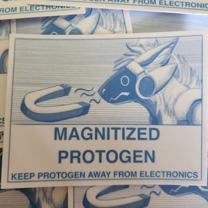May include: A white sticker with a blue and white illustration of a furry creature with a magnet. The text on the sticker reads "MAGNITIZED PROTOGEN KEEP PROTOGEN AWAY FROM ELECTRONICS".