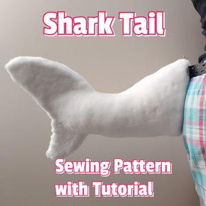 May include: A white shark tail costume with a sewing pattern and tutorial. The tail is attached to a person's waist with a belt.