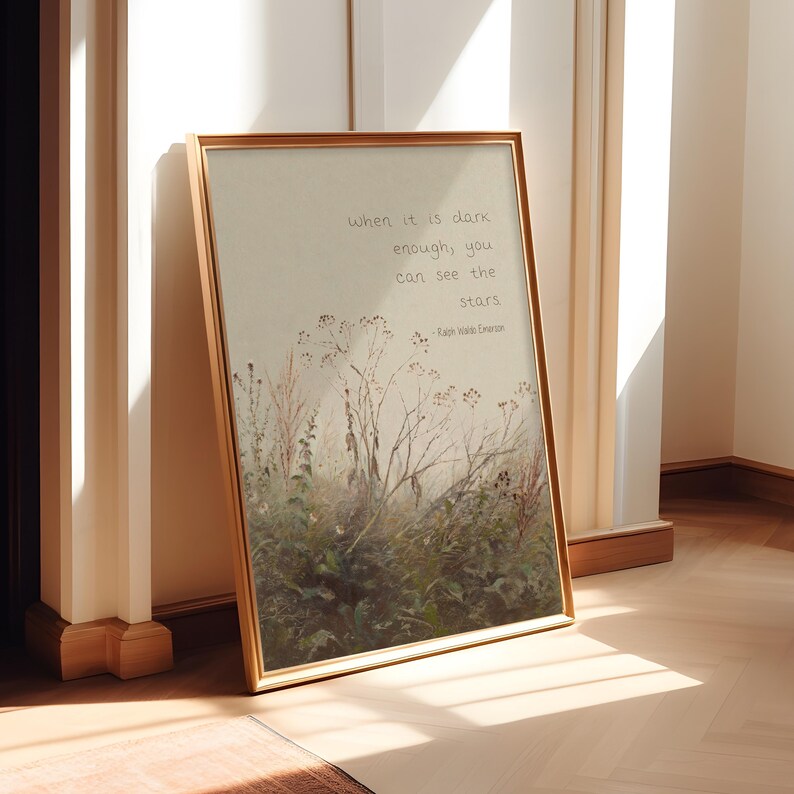 May include: A framed print with a gold-coloured frame. The artwork features a watercolour-style illustration of tall grasses and wildflowers. The text on the print reads, "When it is dark enough, you can see the stars." - Ralph Waldo Emerson.