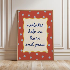 Puede incluir: Un cuadro rectangular enmarcado con fondo rojo terracota y lunares azul claro. Un rectángulo central de color crema con bordes festoneados contiene el texto en cursiva azul oscuro: mistakes help us learn and grow.