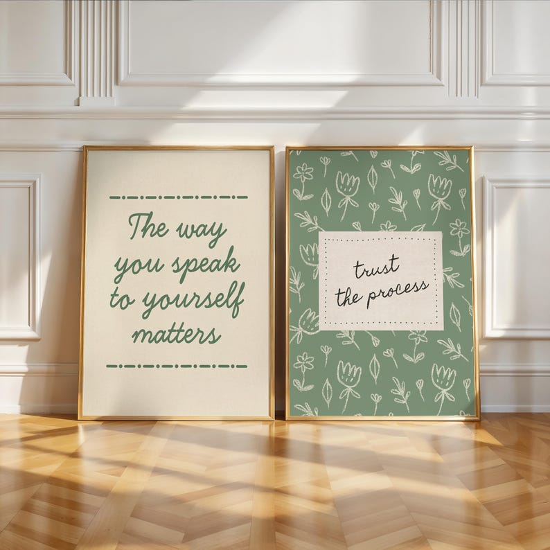 May include: Two framed art prints with gold frames. One print has the text "The way you speak to yourself matters" in green on a cream background. The other print has the text "trust the process" on a green floral background.