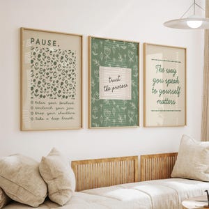 May include: Three framed art prints with inspirational quotes. The first print says "PAUSE" with instructions to relax. The second print says "trust the process". The third print says "The way you speak to yourself matters". All prints have a beige background and are in wooden frames.