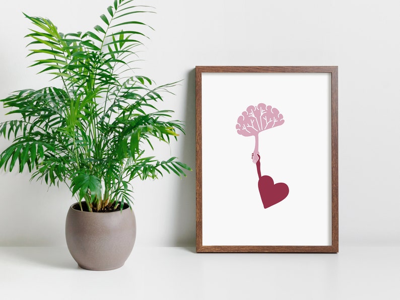Puede incluir: Una impresi&oacute;n enmarcada con un cerebro rosa sosteniendo un coraz&oacute;n rojo. El cerebro est&aacute; estilizado con ramas y el coraz&oacute;n es una forma simple. La impresi&oacute;n est&aacute; sobre un fondo blanco y est&aacute; enmarcada en un marco de madera marr&oacute;n.