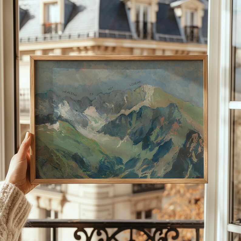 May include: A framed painting of a mountain range with the text "Healing is not linear" written across the top of the mountains.