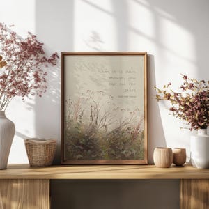 May include: A framed print with the quote, "When it is dark enough, you can see the stars." The artwork depicts a field of plants in muted tones. The frame is brown, and the print is displayed on a wooden shelf with decorative items, creating a calming aesthetic.