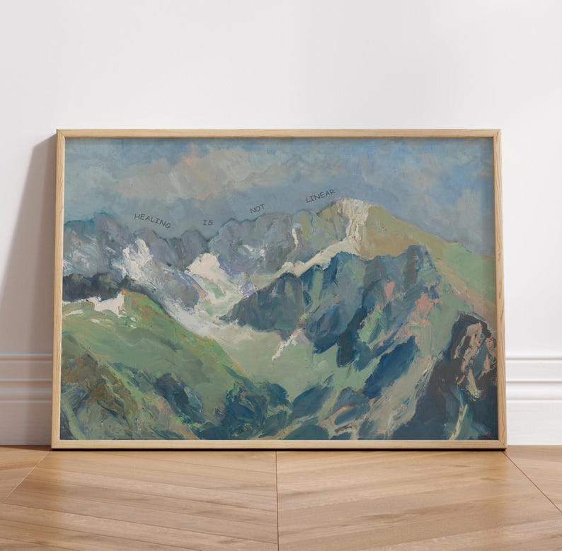 May include: A framed painting of a mountain range with a blue sky and white clouds. The text "HEALING IS NOT LINEAR" is written across the mountains.