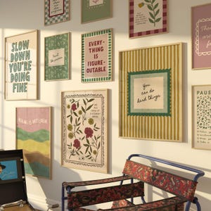 May include: A collection of framed art prints with inspirational quotes and floral designs. The prints feature various colors, including green, pink, and yellow, and are displayed on a white wall. A decorative chair with a red floral pattern is in the foreground.