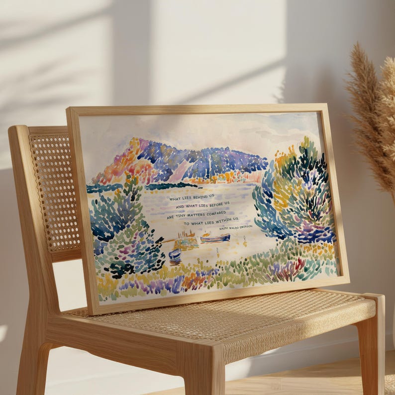 Puede incluir: Una impresi&oacute;n en acuarela enmarcada que presenta un paisaje colorido con un lago, monta&ntilde;as y &aacute;rboles. La obra de arte incluye el texto "WHAT LIES BEHIND US AND WHAT LIES BEFORE US ARE TINY MATTERS COMPARED TO WHAT LIES WITHIN US". La impresi&oacute;n se muestra en una silla de madera.