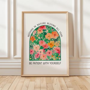Può includere: Un poster bianco con un arco verde pieno di fiori rosa e arancioni. Il testo recita "Niente in natura fiorisce tutto l'anno. Sii paziente con te stesso."