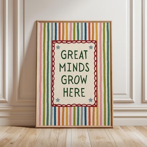 May include: A rectangular framed wall art print featuring a vertical striped background in shades of blue, orange, pink, and green. The center contains a cream-colored rectangle with a dark red scalloped border, four blue stars, and the text GREAT MINDS GROW HERE in dark green.
