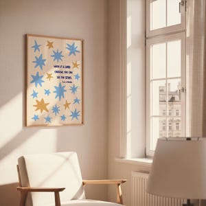 May include: A framed art print featuring a cream-colored background with blue and gold star shapes. The print includes the quote "WHEN IT IS DARK ENOUGH, YOU CAN SEE THE STARS" in blue text, attributed to E.L. Epstein.