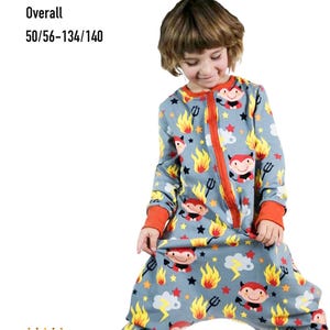 Puede incluir: Mono gris con un estampado de diablo, con detalles en rojo, amarillo y naranja. El mono tiene una cremallera y puños rojos, con la palabra "siesta" y detalles de talla en texto negro. También se ve la marca "Königin Mutter".