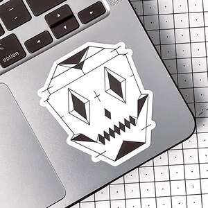 May include: A black and white geometric skull sticker on a silver laptop.