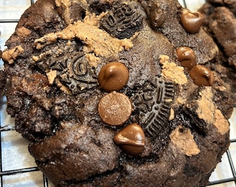 Könnte beinhalten: Nahaufnahme eines Schokoladen-Chip-Kekses mit Schokoladenstückchen und Oreo-Keksstücken. Der Keks liegt auf einem Gitterrost.