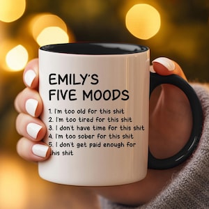 May include: White coffee mug with a black rim and handle. The mug has black text that reads "EMILY'S FIVE MOODS" and a list of five humorous reasons why someone might be in a bad mood.