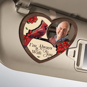Peut inclure: Un porte-visère de voiture en bois en forme de cœur avec un cadre photo et une illustration d'un cardinal rouge. Le texte "I'm Always With You" est imprimé sur le cœur.