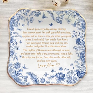 Op de afbeelding: Een vierkant, wit keramisch bord met een blauw bloemmotief en gouden rand. Het bord bevat een oprechte boodschap en is gesigneerd met "Love Mom". Vlinders en bloemelementen versieren de rand.