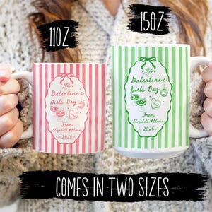 May include: Two white ceramic mugs, one pink and one green, with vertical stripes and the text "Balentine's Girls Day" in an oval design. The mugs are labeled 110 oz and 150 oz. The text "Comes in Two Sizes" is also visible.