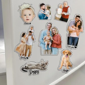 Pu&ograve; includere: Una collezione di calamite in acrilico trasparente con foto di famiglia, tra cui un bambino, coppie e animali domestici. Il testo include "Nana", "family", "I love you!", "Doggy" e "Hugo". Le calamite sono di varie forme e dimensioni, con finitura lucida.