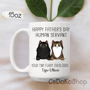 May include: White ceramic mug with a black and brown cat illustration. The mug reads "Happy Father's Day Human Servant Your Tiny Furry Overlords Tiger & Mimir".