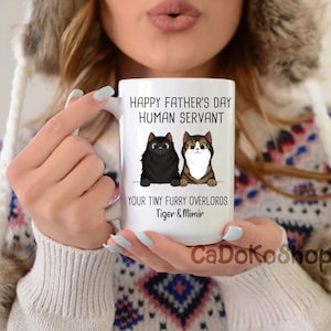 May include: White ceramic mug with a black and brown cat illustration. The mug reads "Happy Father's Day Human Servant Your Tiny Furry Overlords Tiger & Mimir".