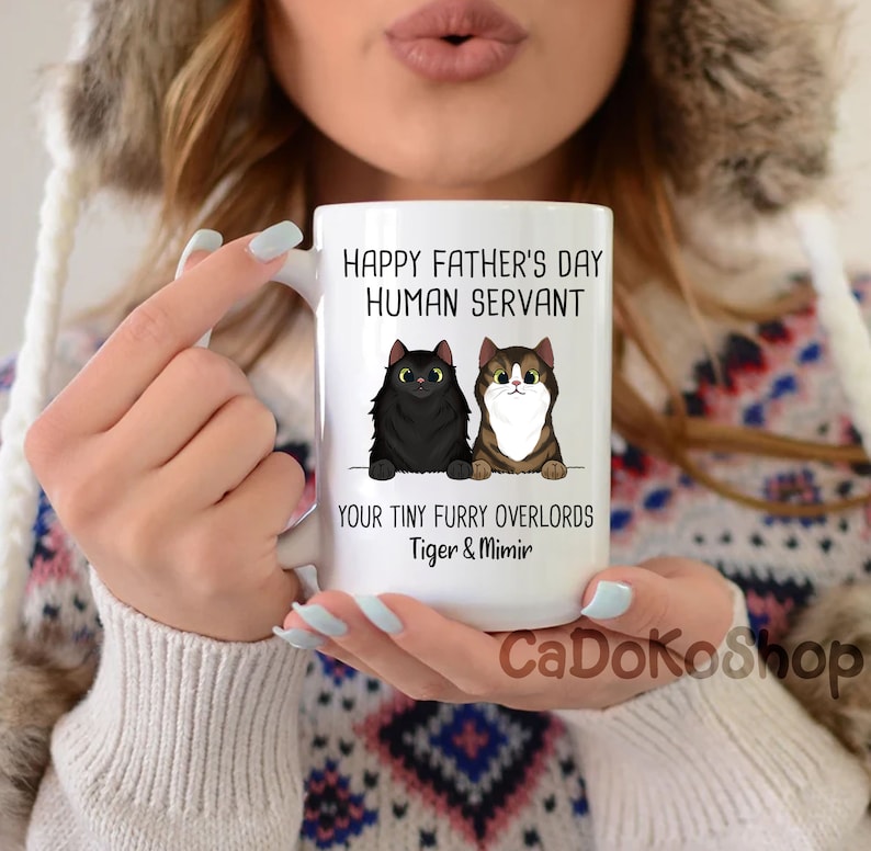 May include: White ceramic mug with a black and brown cat illustration. The mug reads "Happy Father's Day Human Servant Your Tiny Furry Overlords Tiger & Mimir".