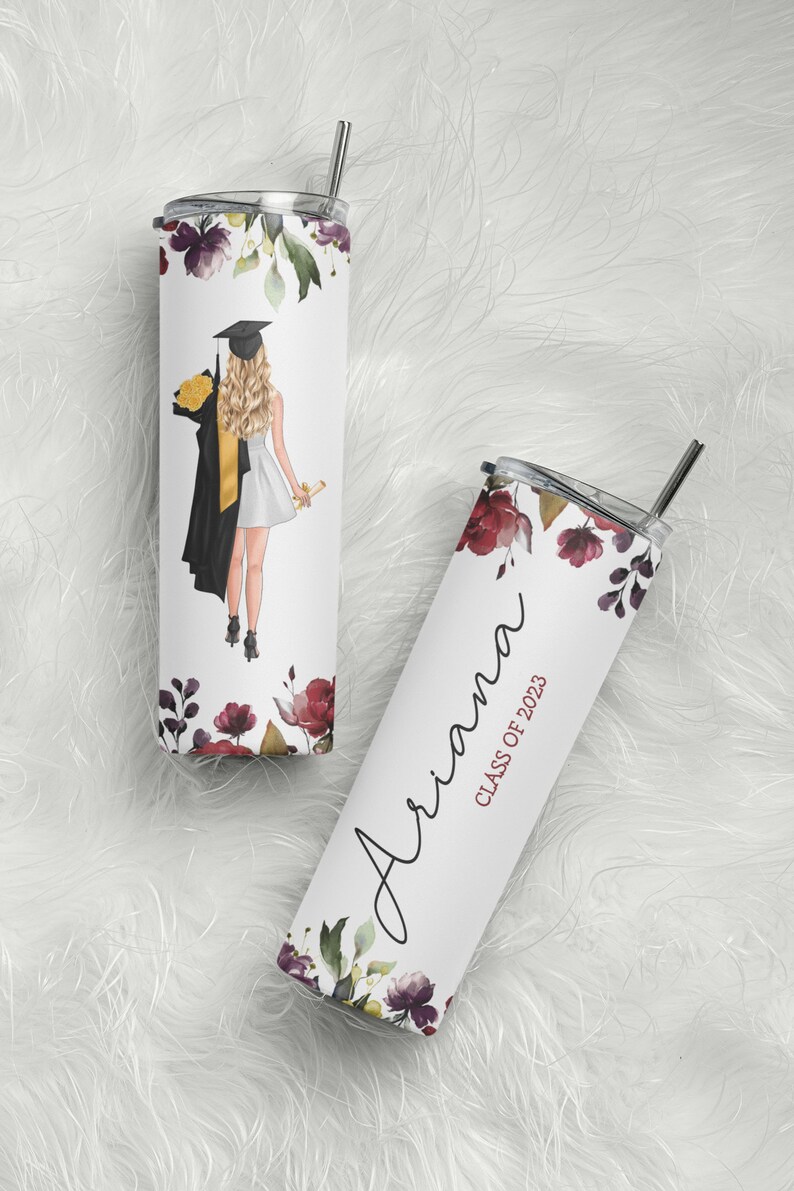 May include: Two stainless steel tumblers with a floral design. One tumbler has a graduation cap and gown illustration and the other has the name "Ariana" and the text "Class of 2023".