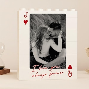 Pode incluir: Uma moldura de foto branca em estilo bloco com uma foto a preto e branco de um casal. A moldura é projetada como uma carta de baralho, com um coração vermelho e a letra "J" no canto superior esquerdo e um coração vermelho com um "Q" no canto inferior direito. As palavras "I love you always forever" estão escritas em vermelho.