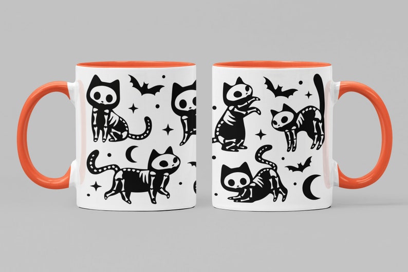 Pu&ograve; includere: Una tazza in ceramica bianca con un bordo arancione presenta un motivo ripetuto di gatti scheletro neri, pipistrelli e lune crescenti. La tazza ha un manico nero.