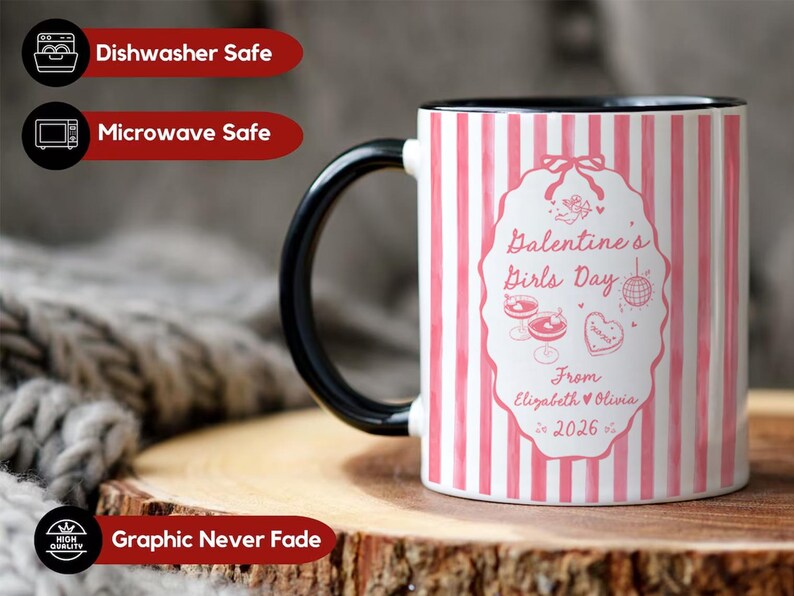 May include: A white ceramic mug with a black handle and rim. The mug features a pink and white striped pattern and a central design with the text "Valentine's Girls Day" and the names "Elizabeth & Olivia 2026".