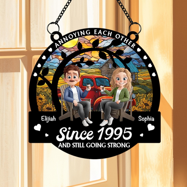May include: A black metal sign with the text "ANNOYING EACH OTHER." It features a couple sitting in chairs, a red truck, and the text "Since 1995 AND STILL GOING STRONG." The names "Elijah" and "Sophia" are also included. The sign has a decorative border.