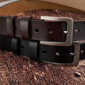 May include: Two leather belts with silver buckles. The top belt is brown and the bottom belt is black.