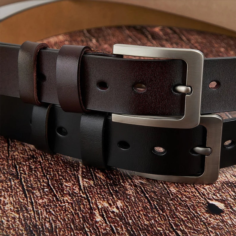 May include: Two leather belts with silver buckles. The top belt is brown and the bottom belt is black.