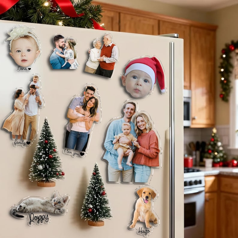 Pu&ograve; includere: Una collezione di calamite trasparenti in acrilico con foto di famiglia, un bambino con un cappello da Babbo Natale, un gattino, un golden retriever e alberi di Natale in miniatura. Le calamite sono su un frigorifero bianco.