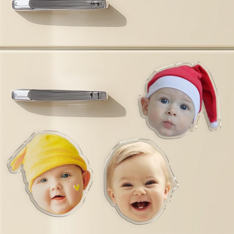 Pu&ograve; includere: Quattro calamite trasparenti in acrilico con facce di bambini. Uno indossa un cappello da Babbo Natale, un altro un cappello giallo e gli altri due non hanno copricapo. Le calamite sono su un frigorifero color crema.