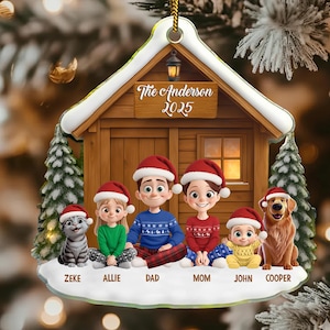 Könnte beinhalten: Personalisierter Weihnachtsschmuck mit einer Familie und ihren Haustieren vor einer Holzhütte. Der Schmuck trägt den Familiennamen "The Anderson" und das Jahr "2025". Jede Figur trägt eine Weihnachtsmütze.