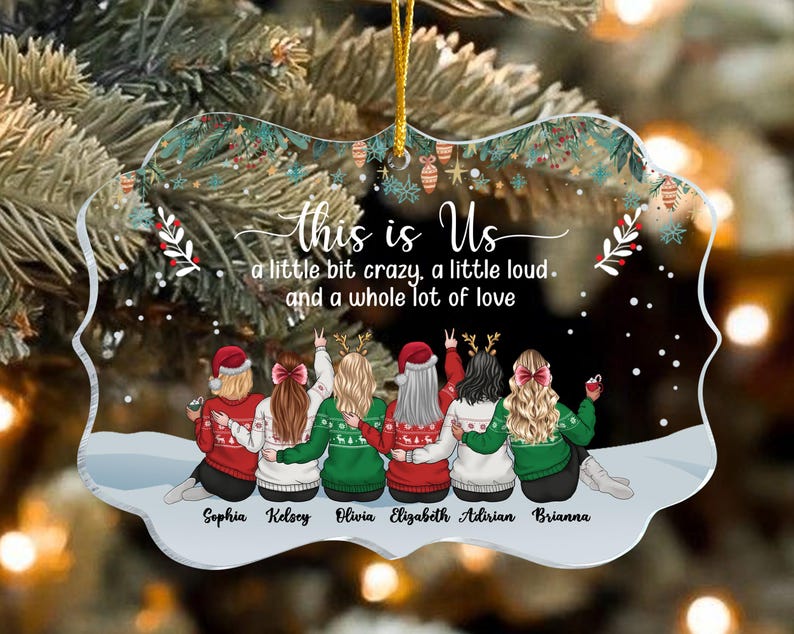 May include: A clear acrylic Christmas ornament with a gold string for hanging. The ornament features six figures in sweaters, with the text "this is Us" and the names Sophia, Kelsey, Olivia, Elizabeth, Adirian, and Brianna.