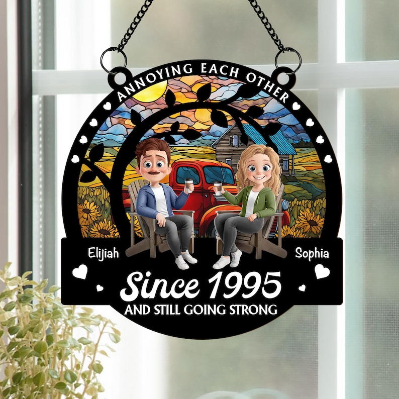 May include: Black metal sign with a chain for hanging. The sign features a couple sitting in chairs in front of a red truck and a house. Text reads "Annoying Each Other" and "Since 1995 and Still Going Strong."