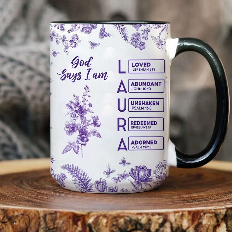 Pu&ograve; includere: Tazza in ceramica bianca con manico e bordo neri, con il nome "LAURA" in lettere viola. La tazza &egrave; decorata con motivi floreali e farfalle e il testo "Dio dice che io sono" e versetti biblici.