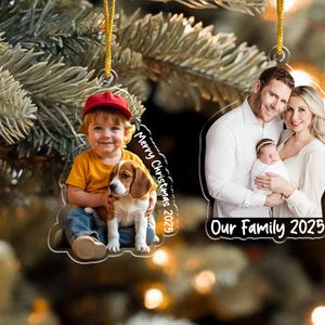 Pu&ograve; includere: Due decorazioni natalizie trasparenti in acrilico. Una presenta un bambino con un berretto rosso che tiene un beagle, con il testo "Merry Christmas 2025". L'altra mostra una famiglia con un bambino, con il testo "Our Family 2025".